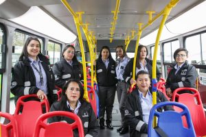 Imagen de un grupo de mujeres conductoras, vestidas de uniforme, posando dentro del interior de un bus